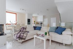 a white living room with a white couch and blue pillows at Exclusive townhouse Maciejki with garden and terrace near Warsaw in Nowa Wola