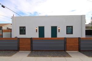 a white house with green doors and a fence at My Casitas in Phoenix