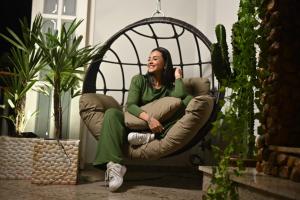 a woman sitting in a chair in a room with plants at Pousada Vale Valparaíso Inn- Polo gastronômico in Petrópolis +48 photos