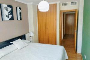 sypialnia z białym łóżkiem i drewnianymi drzwiami w obiekcie Modern Apartment Málaga 80 m² + Balcony w Maladze