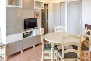 a dining room with a table and a tv at Appartement lumineux Roquebrune 45m² avec piscine partagée in Roquebrune-sur-Argens
