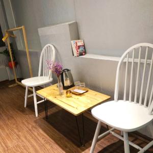 two white chairs and a wooden table with flowers on it at Luna Homestay in Hanoi