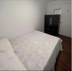 a white bed in a room with a black refrigerator at Self-service small breakfast private Room 1 in Montreal