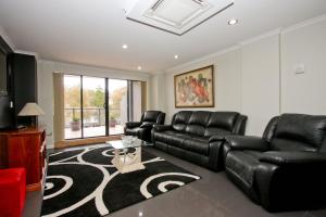 a living room with black leather furniture and a rug at Nautilos On The Harbour in Newcastle