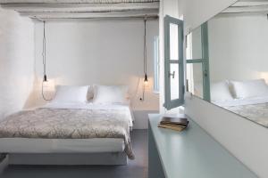 a white bedroom with a bed and a window at Coco-Mat Eco Residences Serifos in Vayiá