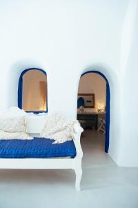 a bedroom with a blue and white bed and two mirrors at Blu Bianco Cave House in Oia