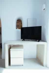 a white table with a television on top of it at Blu Bianco Cave House in Oia +11 photos