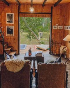 ein Wohnzimmer mit zwei Sesseln und einer großen Glasschiebetür in der Unterkunft Cabana aconchegante em meio à natureza in Morro Reuter