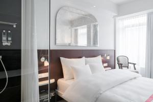 una camera da letto con un letto bianco e uno specchio di Ruby Coco Hotel Dusseldorf a Dusseldorf Altre 30 foto
