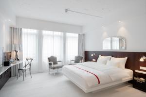 una camera con un grande letto e una scrivania con sedie di Ruby Coco Hotel Dusseldorf a Dusseldorf
