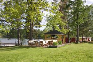 a gazebo with a table and chairs next to a lake at Woikoski Feeling - Kirjokiven Kartano in Joutsenlahti