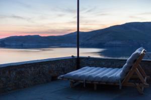 a lounge chair on a wall with a view of the water at Coco-Mat Eco Residences Serifos in Vayiá