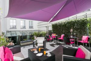 a patio with tables and chairs and a purple umbrella at Hôtel Le Bellechasse Saint-Germain in Paris