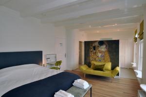 een slaapkamer met een groot bed en een gele stoel bij Boetiek Hotel Kampen in Kampen