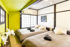 two beds in a room with yellow walls and windows at MIYABI Tateishi in Tokyo