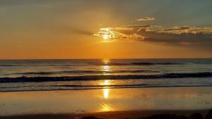a sunset on the beach with the ocean at Beachside Home, Heated Pool, Steps 2 beach, Meticulous, 5-star Rated in Coquina Gables