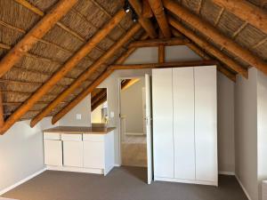 an attic room with white cabinets and a wooden ceiling at Jongensfontein Beachside Villa in Jongensfontein