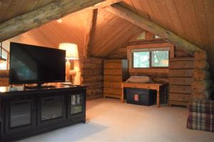 a living room with a flat screen tv in a cabin at Cascade Log Cabin | Mt Rainier, WIFI, Log Cabin in Packwood