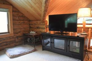 a living room with a flat screen tv on a cabinet at Cascade Log Cabin | Mt Rainier, WIFI, Log Cabin in Packwood +6 photos