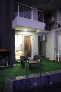 a house with a green yard with chairs and a table at Ivy Bliss Studio with Common Pool, B 14, Karjat in Karjat