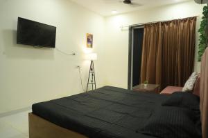 a bedroom with a bed and a flat screen tv at Ivy Bliss Studio with Common Pool, B 14, Karjat in Karjat