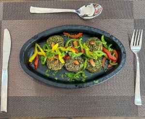 a black plate of food with vegetables on a table at Ivy Bliss Studio with Common Pool, B 14, Karjat in Karjat