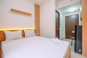 a bedroom with a white bed and a tv at Simply and Nice Studio at Transpark Cibubur Apartment By Travelio in Depok +12 photos