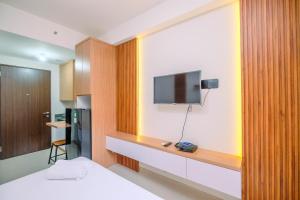 a room with a bed and a tv on a wall at Simply and Nice Studio at Transpark Cibubur Apartment By Travelio in Depok