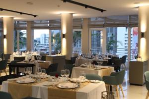 マプトにあるMontebelo Girassol Maputo Hotelの白いテーブルと椅子、窓のあるレストラン