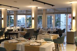 un restaurante con mesas y sillas blancas y ventanas en Montebelo Girassol Maputo Hotel, en Maputo