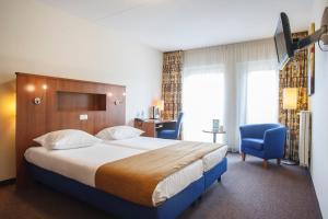 a hotel room with a bed and a blue chair at De Borgh in Zevenbergen