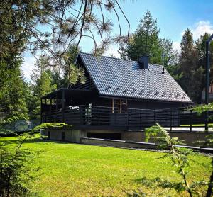 una casa con un tetto nero in cima a un cortile di Czarna Chata Beach & SPA a Klimkówka Altre 120 foto