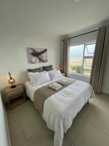 a bedroom with a large bed with a large window at 9 Dolphin Bay, Aston Bay in Jeffreys Bay +18 photos