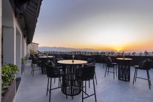 a restaurant with tables and chairs on a balcony with the sunset at Clarks Inn Dehradun in Dehradun