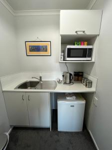 a small kitchen with a sink and a microwave at Kaimai Sunset Bed & Breakfast in Matamata