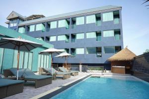 a swimming pool with chairs and umbrellas in front of a building at Phattrasom Villa in Cha Am