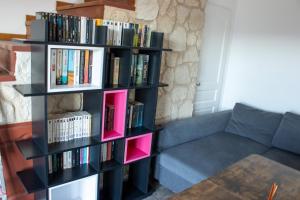 a black book shelf filled with books next to a couch at Chambres d'hôtes Les Nymphéas in Revest-les-Roches