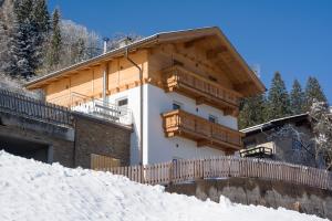 a house with a wooden balcony on top of snow at Bergchalet Emberg in Aschau