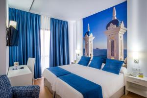 ベニドルムにあるHotel Avenidaの大きなベッドと青いカーテンが備わるホテルルームです。