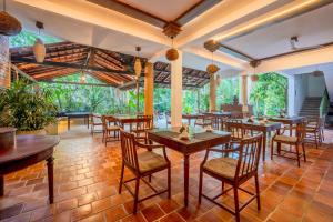 a restaurant with wooden tables and chairs and large windows at Aurora in Unawatuna