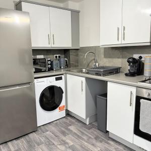 a kitchen with white cabinets and a washer and dryer at Newly Furnished Modern 2 Bedroom Flat With Free Parking in Humberstone Leicester in Leicester