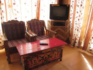 a living room with two chairs and a table and a tv at New Moon Guest House in Leh