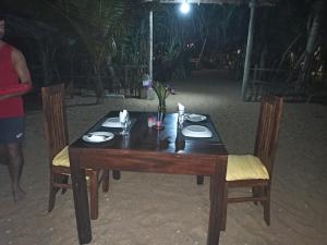 - une table en bois avec 2 chaises et des assiettes dans l'établissement Ravana - Beach CABANAS, à Hikkaduwa