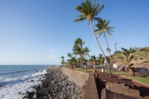 a beach with palm trees and a retaining wall at Hotel Austral by Exsel in Saint-Denis