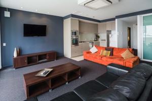 a living room with an orange couch and a tv at Honeysuckle Executive Suites in Newcastle