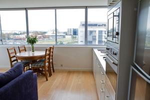 cocina con mesa y comedor con ventanas en Honeysuckle Executive Suites en Newcastle