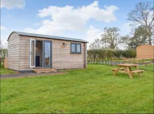 a tiny house in a field with a picnic table at Vicarage Hideaways in Halvergate