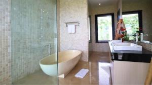 a bathroom with a large tub and a sink at Villa Aventus Uluwatu in Uluwatu