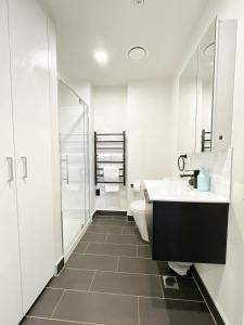 a white bathroom with a toilet and a sink at Chic Downtown 1Bed Aircon Apt with Pool Gym Sauna Near Skytower in Auckland