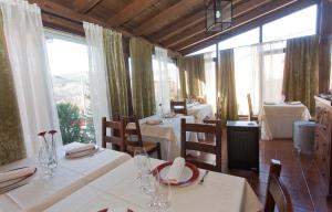 a restaurant with white tables and chairs and large windows at Hotel Rural El Yantar de Gredos in San Martín del Pimpollar
